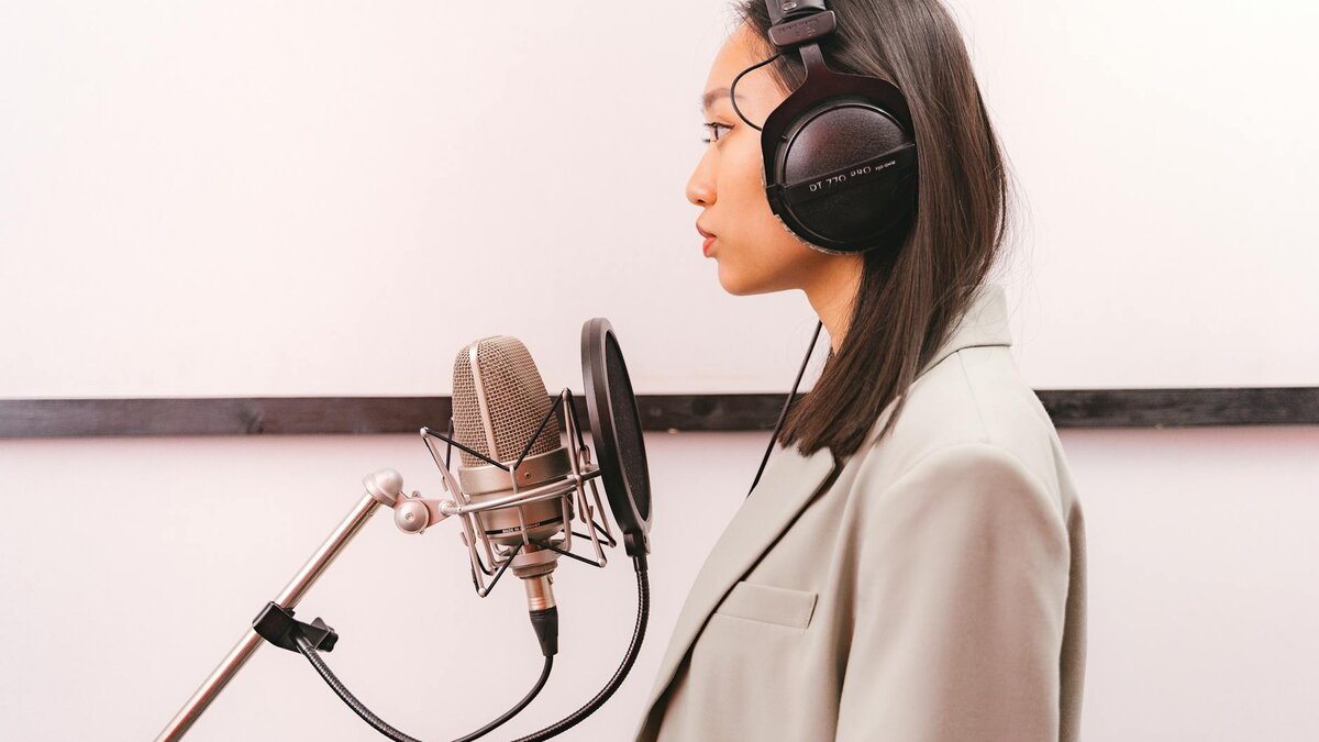 Voice actor recording in professional studio with microphone and studio headphones